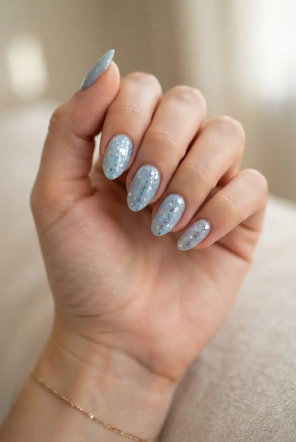 Light blue foil speckle nails with scattered metallic flakes over a glossy base.