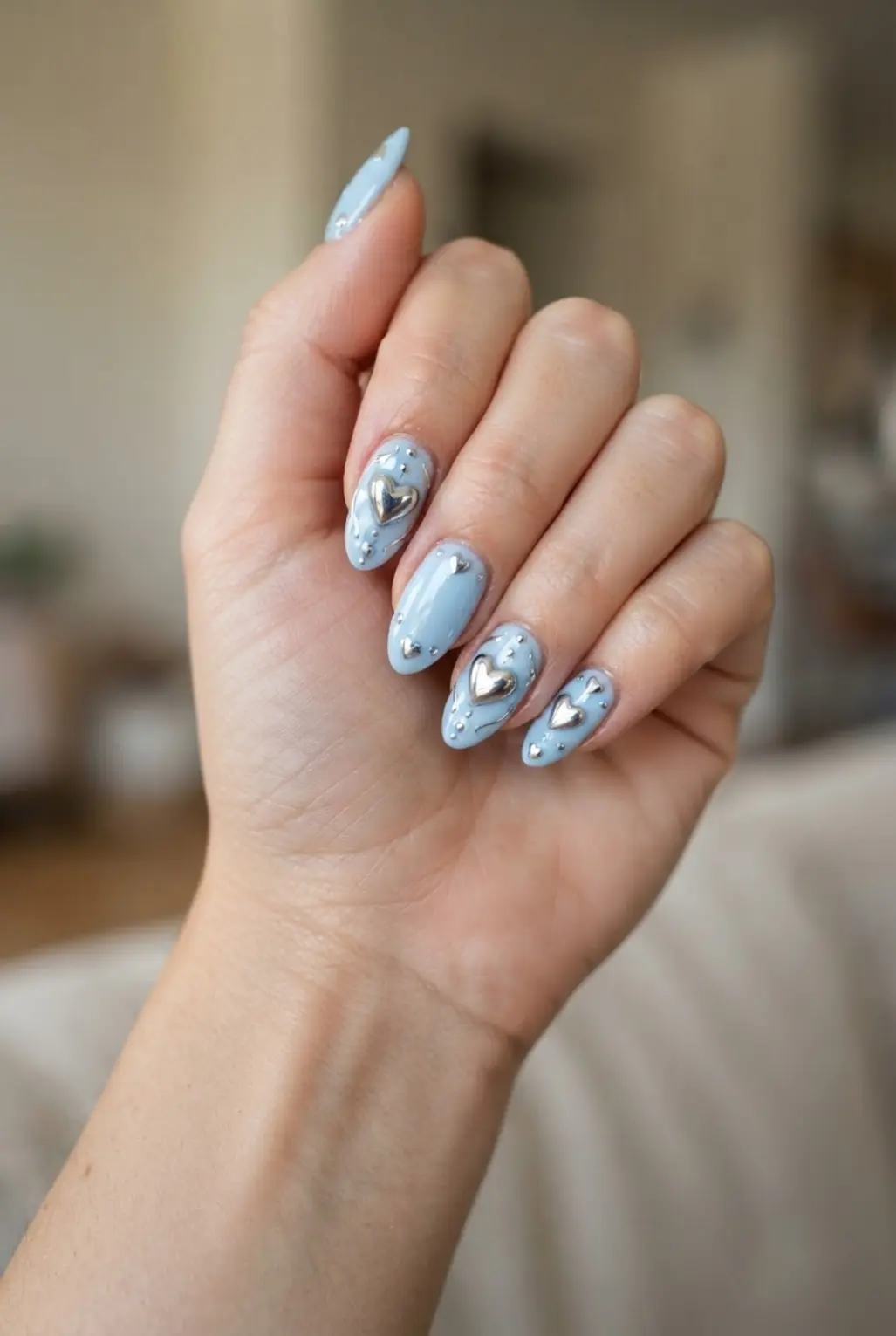Light blue chrome heart nails with reflective silver hearts and rounded tips.
