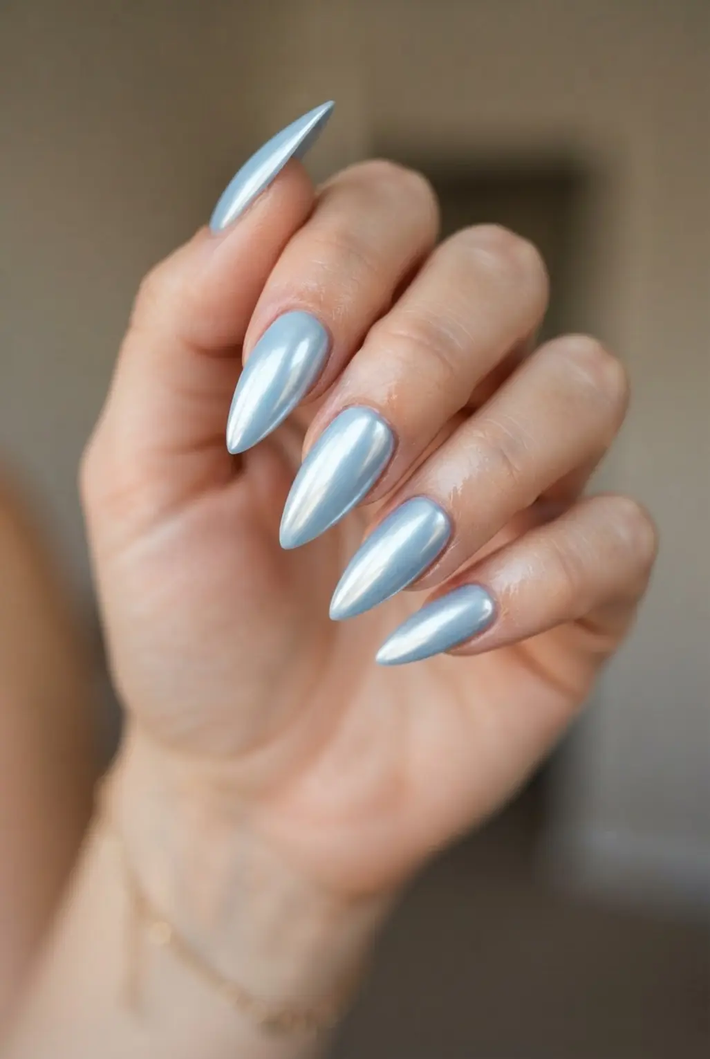 Glossy light blue chrome stiletto nails with reflective glazed surfaces and sharp tapered tips.