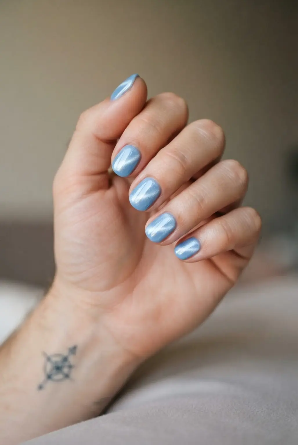 Light blue cat eye magnetic nails with a bright diagonal beam and glossy gel finish.