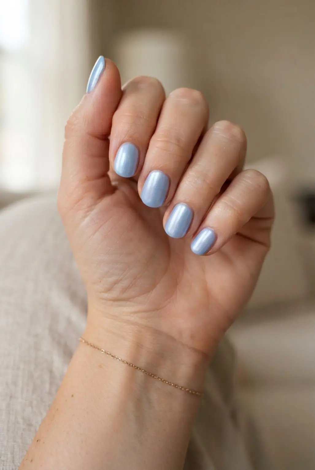Soft blue pearl finish rounded nails with pearly reflections and smooth polish.