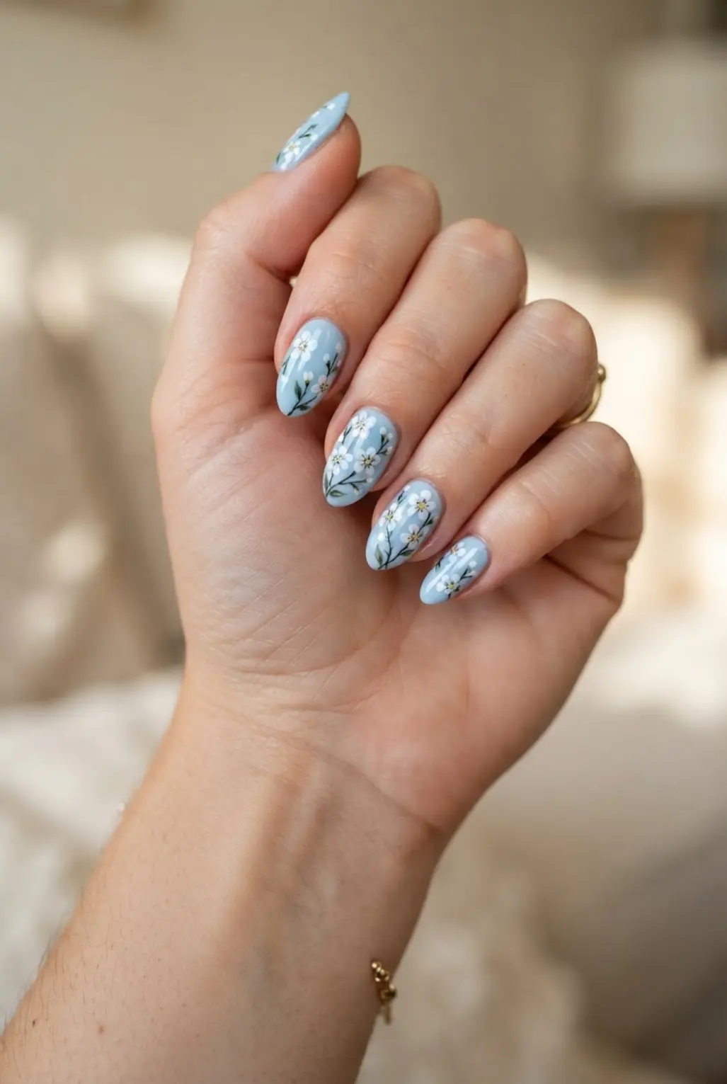 Light blue floral nails with small white blossoms, thin stems, and glossy blue color.