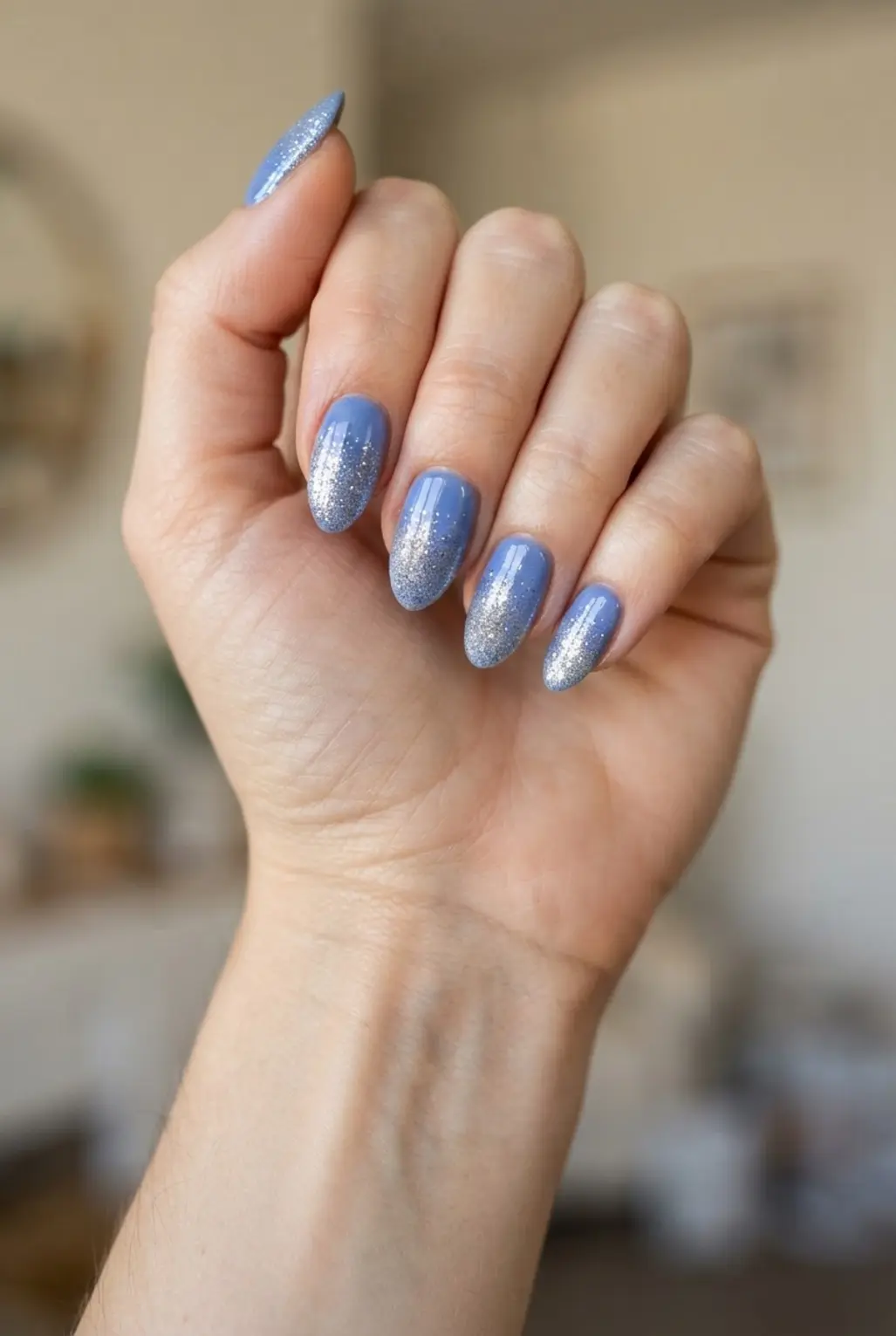 Periwinkle blue glitter gradient nails with sparkle near the tips and a soft fade.